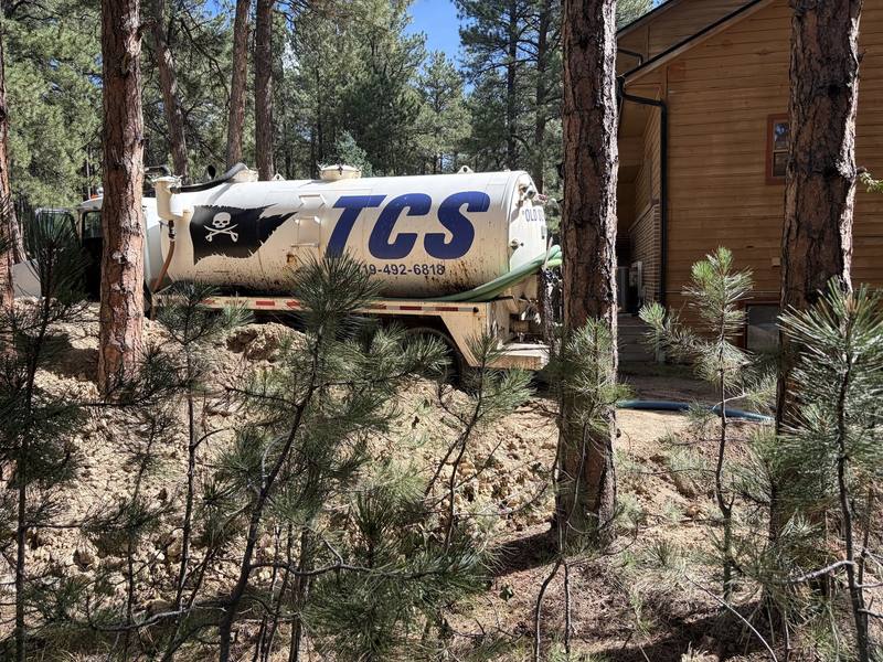 TCS Septic pump truck parked among pine trees at a mountain property